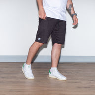HEAVY DUTY shorts in black on male model, side view displaying the mid-thigh length and comfortable loose fit for movement
